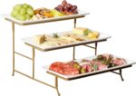Three-tier serving set with white rectangular plates and a gold metal stand, displaying various snacks.