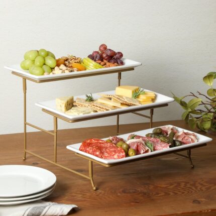 Three-tier serving set with white rectangular plates and a gold metal stand, displaying various snacks.