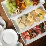 Three-tier serving set with white rectangular plates and a gold metal stand, displaying various snacks.
