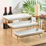 A three-tier Gomakren serving stand with gold frame and white rectangular porcelain platters, displaying various desserts.