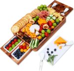 A large hecef acacia wood charcuterie board set with cheese, crackers, and fruit, showing the pull-out drawers and knife set.