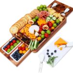 A large hecef acacia wood charcuterie board set with cheese, crackers, and fruit, showing the pull-out drawers and knife set.