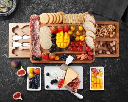 A large hecef acacia wood charcuterie board set with cheese, crackers, and fruit, showing the pull-out drawers and knife set.