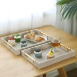 Two rectangular ivory faux shagreen serving trays with brushed gold handles, one larger and one smaller, stacked slightly.